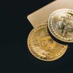 Close-up image of two gold bitcoin coins on a dark background, symbolizing cryptocurrency.