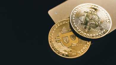 Close-up image of two gold bitcoin coins on a dark background, symbolizing cryptocurrency.