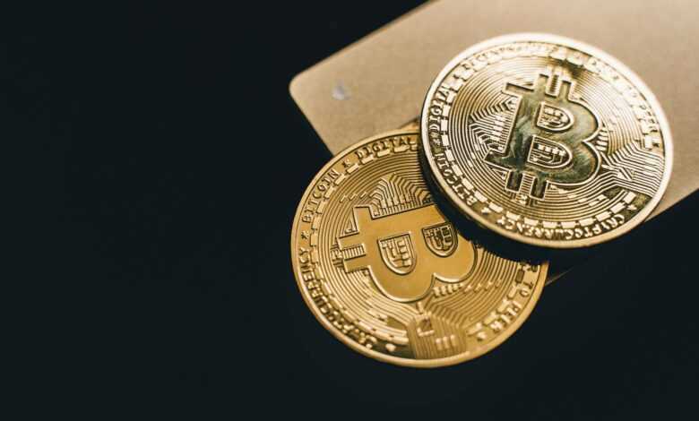 Close-up image of two gold bitcoin coins on a dark background, symbolizing cryptocurrency.