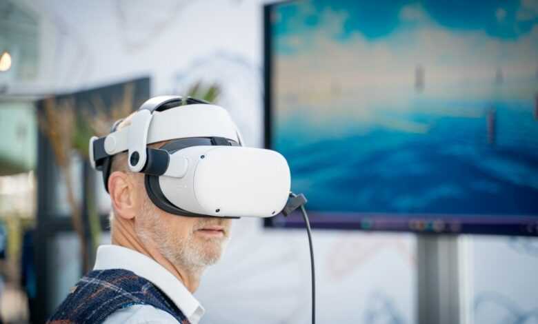 A man wearing a virtual reality headset in front of a laptop